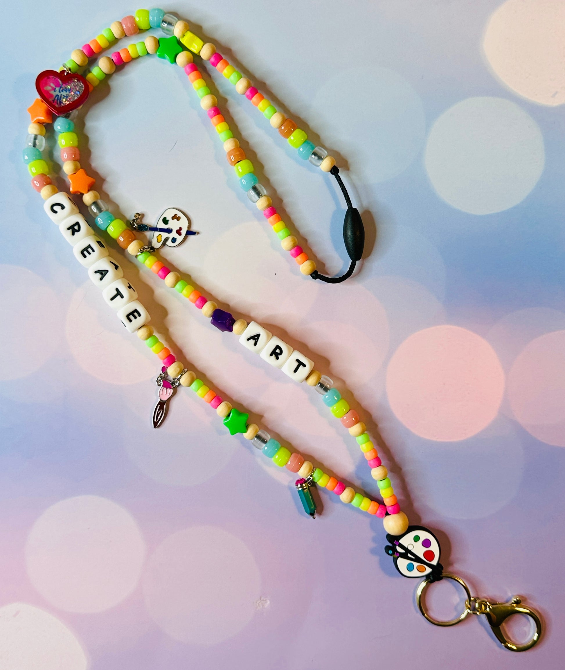 The paint palette, brush, pencil, and heart charms that are on the lanyard.