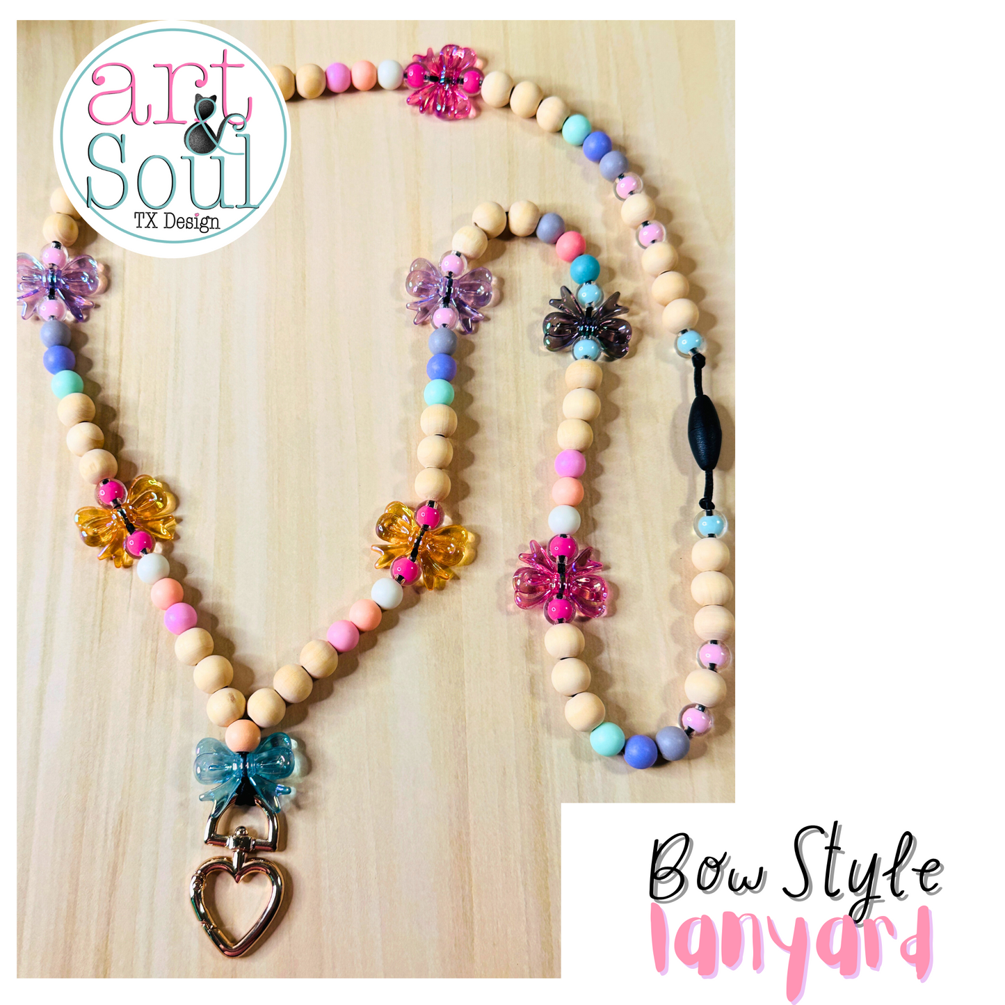 A full view of a bow style lanyard for teachers on a wooden background.  The colorful bows, heart-shaped keychain, colorful beads, and breakaway clasp are shown.