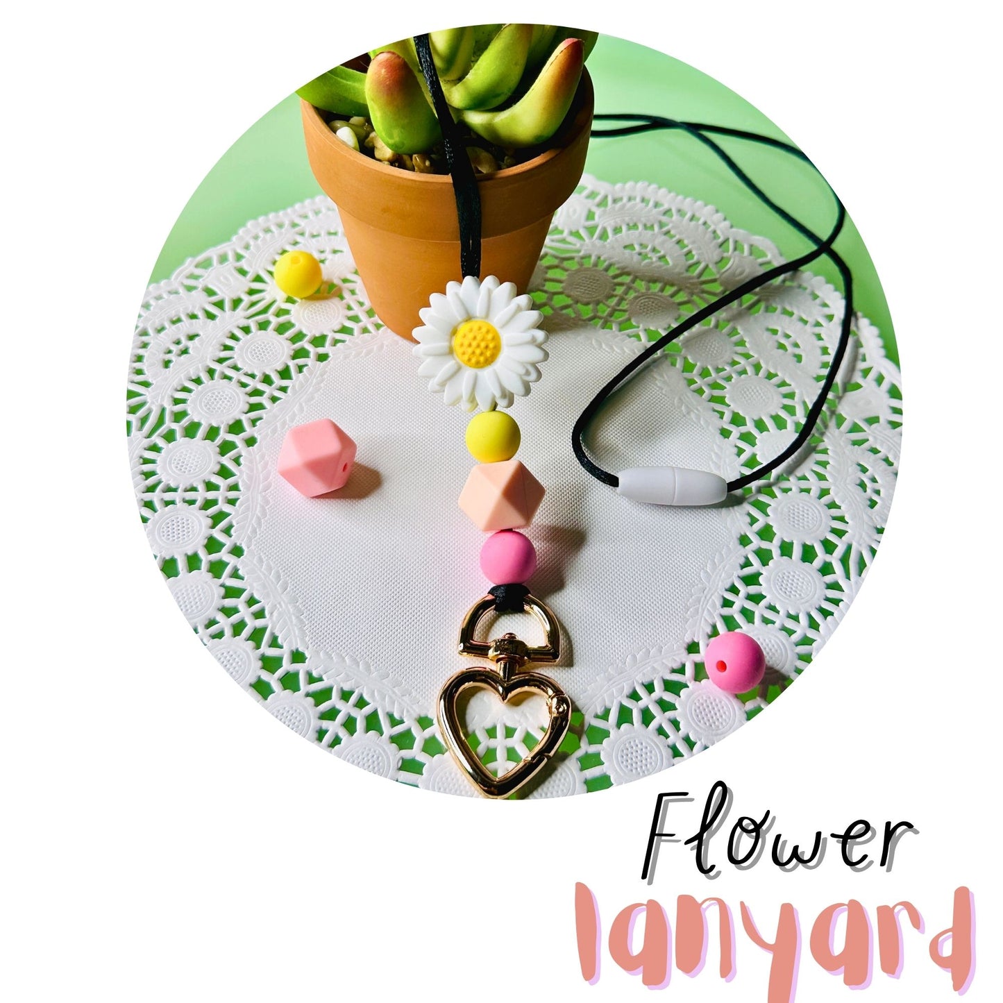 The Flower Lanyard draped over a potted succulent on a green table and white doillies.