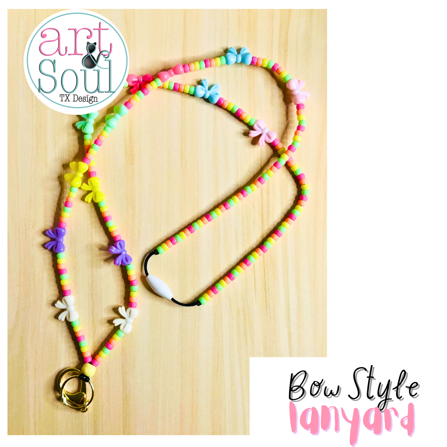 The Mini Bow Lanyard on a wooden table.  The rainbow colored beads, bows, keychain, and breakaway clasp can be seen.