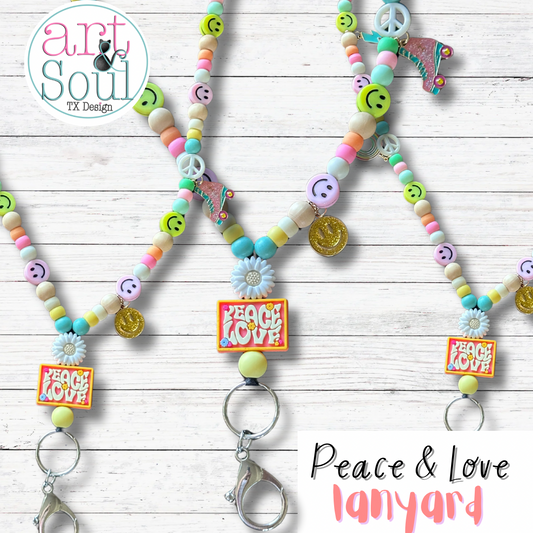 A trio of Peace And Love lanyards on a white wooden backdrop.  The silicon Peace and Love sign, metal roller skate and smiley face charms, and pastel colored beads and happy faces can be seen.