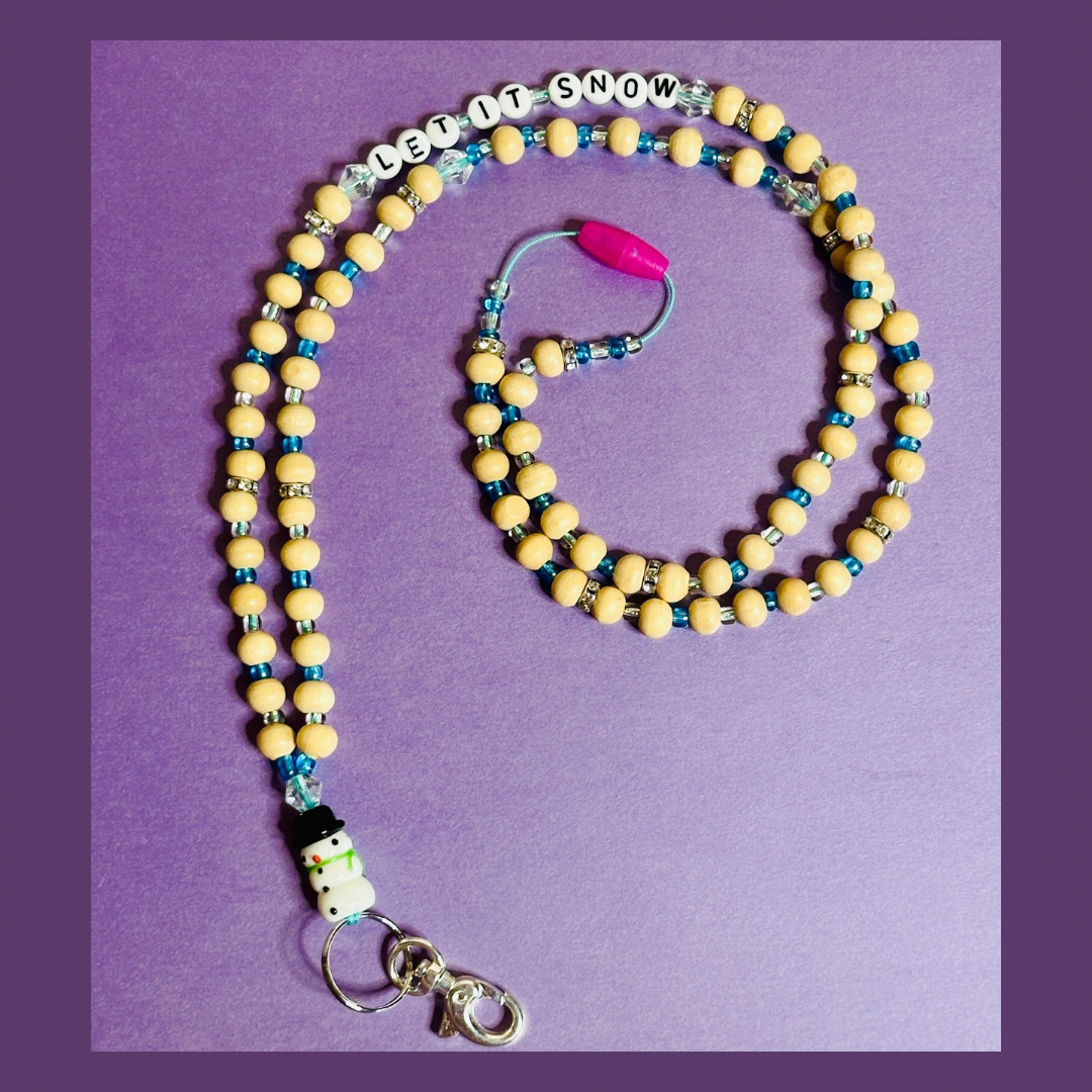 The full Snowman Christmas Lanyard on a purple background.  The lanyard is in a spiral shape and the beaded words "LET IT SNOW" are seen on the top string of the lanyard.