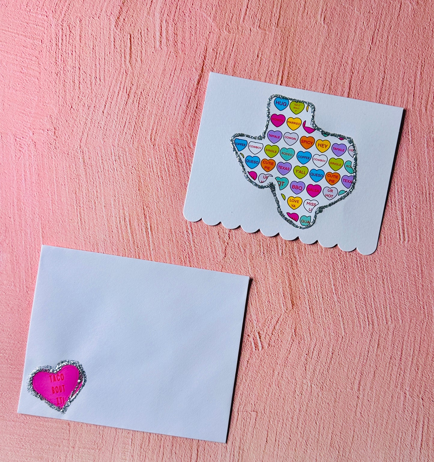 A white Texas Valentine's Day card and envelope on a pink background.